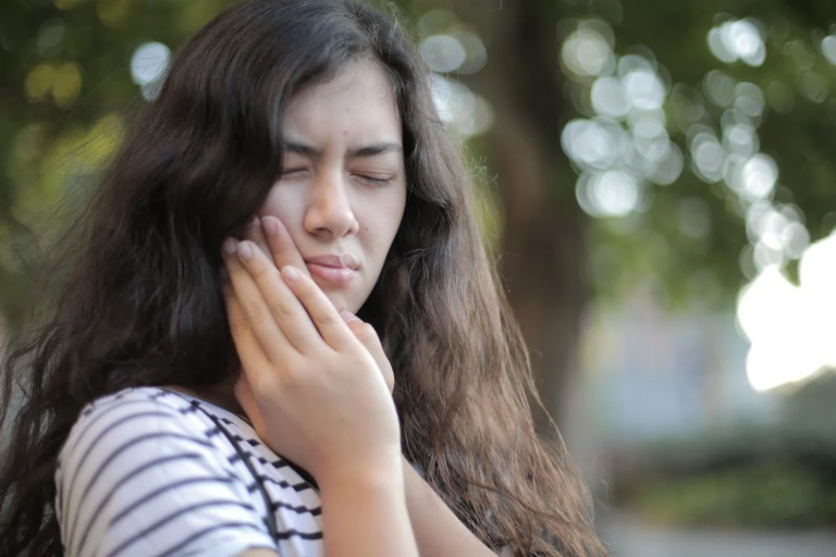 a woman cupping her jaw due to tooth pain and sensitivity