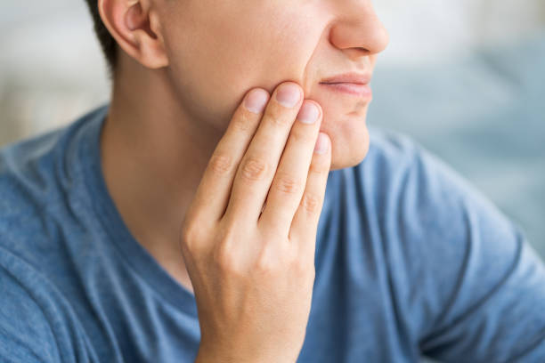 a man pressing his jaw due to tooth pain