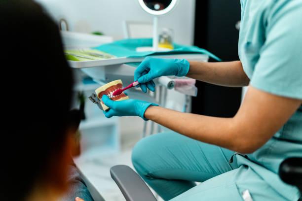 dentist teaching how to brush teeth to patient at dentist's office