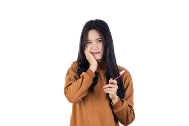 woman have a toothache holding toothbrush