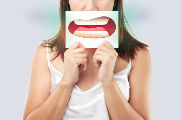 a woman holding an illustration of teeth in front of her mouth